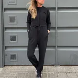 Mono largo negro de corte holgado, con cuello redondo, mangas largas, cierre frontal con botones a presión, bolsillos en el pecho y laterales, y cintura ajustable con cordón.