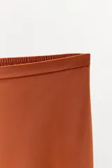 Pantalón de tiro medio confeccionado en tejido satinado, con cintura elástica y pernera recta. Presenta detalles de encaje y bordados en contraste en el ruedo.