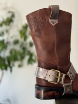 Bota de cuero marrón con estribo desmontable plateado.