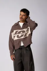 Campera tejida de punto con cierre frontal completo, cuello tipo polo y diseño con franja horizontal en contraste con estampado gráfico. Presenta puños y ruedo acanalados, con corte holgado.