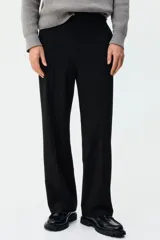 Pantalón de corte relajado color negro, con cintura elástica, cierre frontal con botón y cordón de ajuste oculto. Presenta piernas con raya marcada, bolsillos laterales al bies y bolsillos traseros ribeteados con botón.
