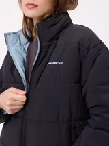 Campera puffer reversible de la marca Rusty, con diseño capitoneado. Presenta cuello alto, cierre frontal completo y logo bordado en el pecho. El interior es de un tono contrastante.