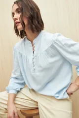 Camisa verde claro de viscosa suave, con cuello mao y botonadura parcial al frente. El detalle de frunces en los hombros y los puños abotonados le suman delicadeza y estilo.