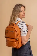 Mochila de cuero sintético color suela, con compartimento principal amplio, bolsillo frontal con cierre y correas ajustables.