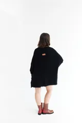 Poncho celeste de tejido de punto con cuello redondo y terminación desflecada.