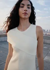 Vestido largo de punto acanalado en color blanco, con diseño entallado y cuello redondo. Presenta un estilo asimétrico en la parte superior con una manga corta y un hombro descubierto.