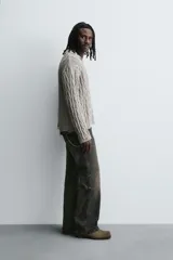 Polo de algodón tejido con estructura de trenzas, cuello solapa con abertura frontal en V y manga larga. Presenta acabados en rib con efecto roto en puños, cuello y ruedo.