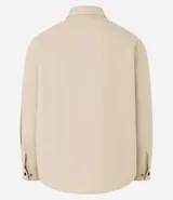 Camisa de manga larga confeccionada en sarga de algodón color verde menta, con cuello inglés y cierre frontal de botones negros. Presenta dos bolsillos de parche con solapa en el pecho y puños con botones.
