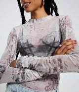 Blusa de manga larga y cuello alto en tejido de tul transparente, con estampado que simula textos manuscritos y un diseño gráfico de corsé en tonos grises y rosados.