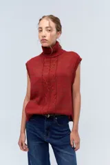 Chaleco de punto color ladrillo con cuello alto y diseño trenzado en el frente.