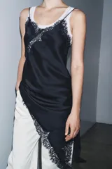 Vestido corto de satén con escote en pico y tirantes finos. Presenta aplicaciones de encaje en el escote y en el bajo, con un diseño asimétrico y abertura lateral.