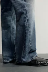 Jeans flare fit de denim negro, tiro medio, ajustados arriba y con botamanga acampanada. Cuentan con cinco bolsillos, lavado efecto gastado y bajo con acabado irregular. Cierre frontal con cremallera y botón.