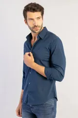 Camisa de manga larga color azul marino, con cuello clásico, cierre frontal de botones y corte recto. Presenta un diseño minimalista con logo bordado sutil en el pecho.