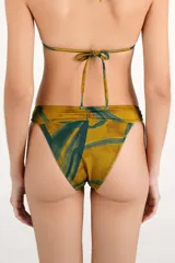 Calzón de bikini estampado en tonos mostaza y verde, con detalles de aros metálicos en los laterales.