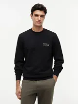 Buzo negro de cuello redondo de Tommy Hilfiger, con el logo brand love bordado en el pecho, mangas largas y puños acanalados.