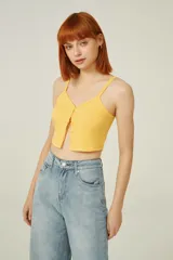 Top amarillo de breteles finos, confeccionado en poliéster de punto canalé, corte al cuerpo, con botones y cuello en V.