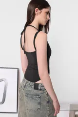 Body negro de microfibra, corte ajustado, con escote redondo y breteles finos. Presenta tiras cruzadas en la espalda y broches a presión en la entrepierna.