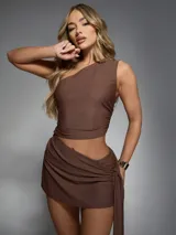 Vestido corto marrón de un hombro con corte en la cintura y falda drapeada con nudo en la cadera.