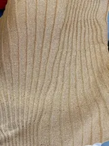 Chal de punto color beige con textura acanalada y sutil brillo metalizado.