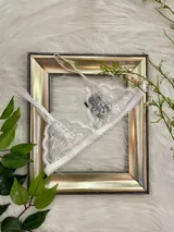 Bralette de encaje blanco con diseño triangular, breteles regulables y cierre de gancho en la espalda.