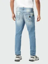 Jeans de corte recto para hombre, color celeste claro con efecto lavado y desgaste sutil. Presenta un pequeño parche con el logo hexagonal de Philipp Plein en el bolsillo superior izquierdo.