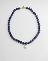 Collar de cuentas de piedra sodalita azul con un dije colgante de perla natural en el centro y cierre tipo marinero dorado.