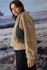 Chaqueta tipo teddy color negro, con capucha, cierre frontal metálico y puños tejidos.