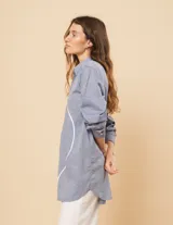 Camisa celeste de algodón con corte oversized, botones frontales a tono y vivos blancos ondulados en el frente.