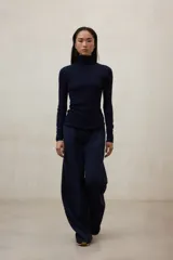 Pantalón negro de tiro alto, corte ancho y pierna recta, con pliegues frontales.