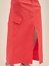 Falda larga color coral, estilo cargo, con cintura ajustable, tajo en el frente y bolsillos laterales.
