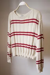 Sweater tejido artesanalmente con hilado 70% algodón y 30% acrílico, color crudo con rayas horizontales rojas.