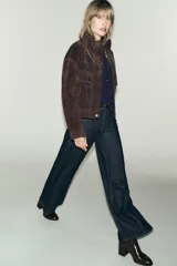 Botín de tacón alto en bloque, con cuerpo de cuero sintético y caña de tejido acanalado. Presenta una tira decorativa con hebilla metálica en el tobillo y acabado en punta.