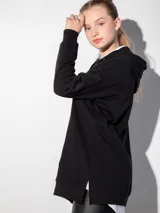 Canguro blanco oversize con capucha, cordones y bolsillo tipo canguro.