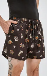Short de baño negro con estampado de estilo tatuaje old school, que incluye diseños de rosas, sirenas, tiburones, anclas y diamantes. Cuenta con cintura elástica, cordón ajustable y cuatro bolsillos.