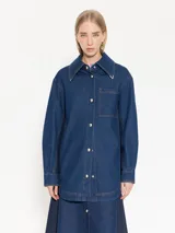 Camisa de denim azul con costadillos y bajo mangas en denim azul marino, punteras metálicas níquel en puntas de cuello, broches semi esfera níquel en centro delantero y puños, bordado JCH de hilo a contra tono en ruedo del lado derecho.