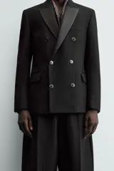 Blazer de corte regular confeccionada en tejido con lana, con diseño de doble botonadura. Presenta solapas de muesca en tejido combinado a tono, manga larga con puños abotonados, bolsillos laterales con solapa y bolsillo de vivo en el pecho.