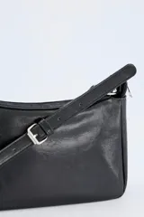 Bolso crossbody de efecto cuero en color negro, con diseño compacto, cierre superior y correa ajustable con hebilla metálica.