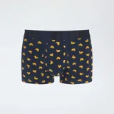 Pack de tres boxers para hombre. Incluye un boxer amarillo liso, un boxer azul marino con estampado de patos amarillos y un boxer azul con estampado de flamencos rosados. Todos tienen cintura elástica con la palabra "ULTIMATE" grabada.