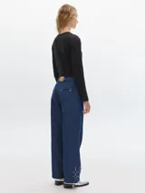 Pantalón jean de pierna ancha, color azul oscuro, con pinzas y detalles de tachas en los bajos. Presenta bolsillos laterales y traseros tipo sastrero.