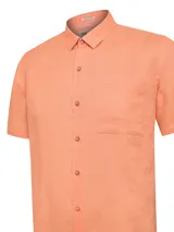 Camisa manga corta RKF de lino orgánico color salmón, con cuello camisero, cierre frontal con botones y un bolsillo ojal en el pecho con detalle bordado.