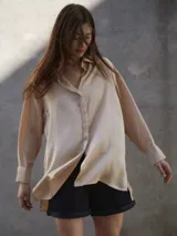 Camisa de seda color beige, de corte amplio y mangas largas con puños. Cierre frontal con botones.