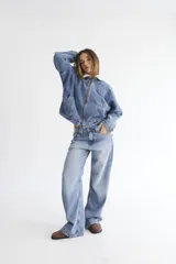 Campera bomber de denim azul oscuro con costuras a contratono en color verde. Presenta cuello de corderito en color marrón, cierre frontal y diseño holgado.