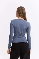 Top de manga larga confeccionado en licra satinada, con diseño ajustado al cuerpo. Presenta un escote con recortes estratégicos y detalles drapeados en el frente que aportan un toque sofisticado.