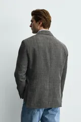 Blazer de corte regular confeccionado en tejido con lana, con cuello de solapas de muesca, cierre frontal de dos botones, mangas largas con puños abotonados y bolsillos de plastrón en la parte frontal.