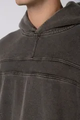 Buzo canguro oversize con efecto lavado desgastado, confeccionado en friza pesada. Presenta diseño con recortes, capucha amplia y puños y ruedo acanalados.