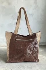 Cartera de cuero combinada en tonos beige, marrón y detalles con estampado animal print tipo vaqueta, con doble asa de hombro y diseño estructurado.
