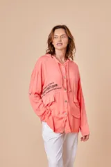 Campera color salmón con capucha, cierre frontal con botones y bolsillos delanteros con solapa. Estampado con texto en el frente.