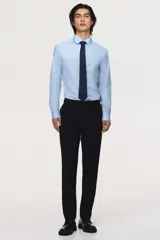Camisa de manga larga color celeste claro, con cuello italiano y tapeta lisa con botones blancos. Presenta un corte ajustado (slim fit) y bajo redondeado.