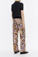 Pantalón de pana con estampado floral en tonos rosa, naranja y negro. Modelo de corte recto con largo tobillero, cierre con botón y cremallera frontal, bolsillos laterales en delantero y plastrón en la parte posterior.