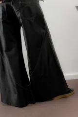 Pantalon de cuero ovino italiano con tiro medio y piernas anchas. Presenta cortes diagonales que aportan volumen y vuelo a la prenda, con detalles de costuras a contratono y pretina con pasacintos en gamuza al tono.